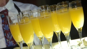 A waiter holds a tray of mimosas.