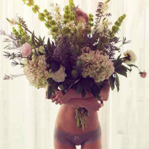 A woman carrying a large bouquet of flowers and wearing panties from Lille Boutique
