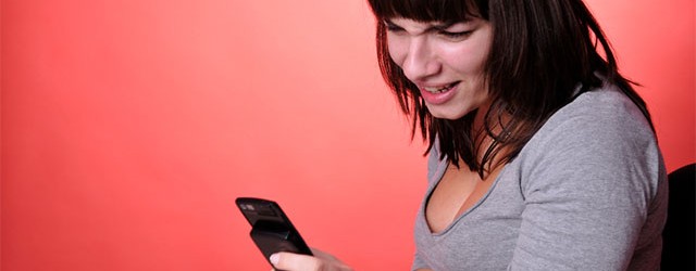 A young woman looks confused by a text message.