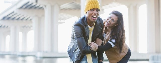 A playful young multi-racial couple, stylishly dressed.