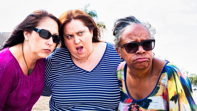 Three women watching a neighbor with outraged expressions.