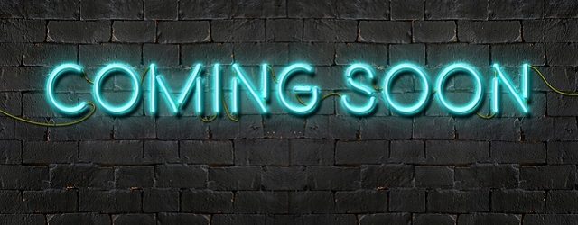 "COMING SOON" neon sign shining on black brick wall