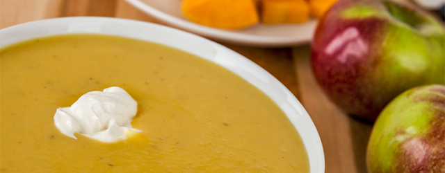 Butternut squash soup, in a bowl and apples on the table beside it