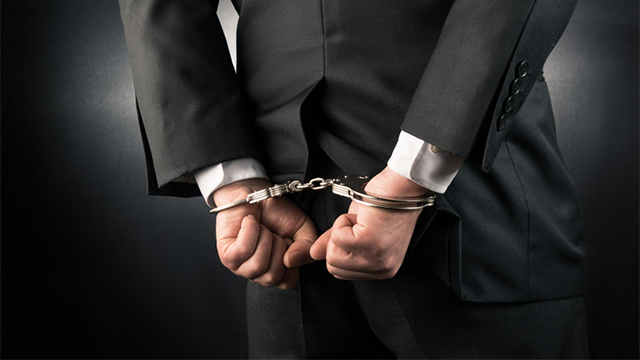Businessman with his hands cuffed behind his back