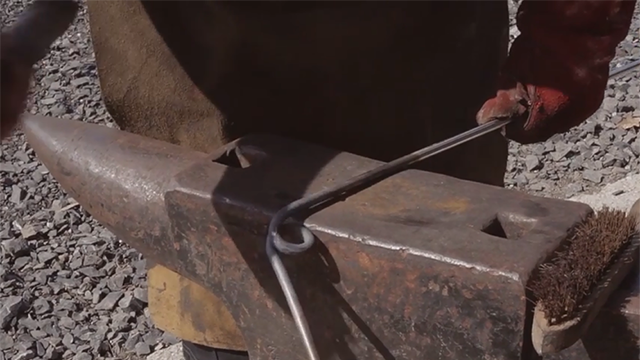 A blacksmith works at an anvil