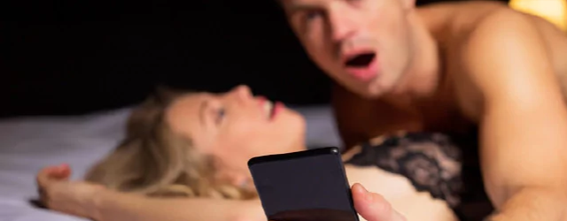 A young person looks at their phone while having sex