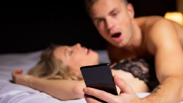 A young person looks at their phone while having sex