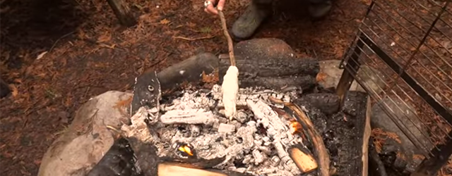 bread cooking on a stick over a fire