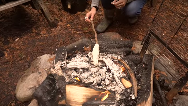 bread cooking on a stick over a fire