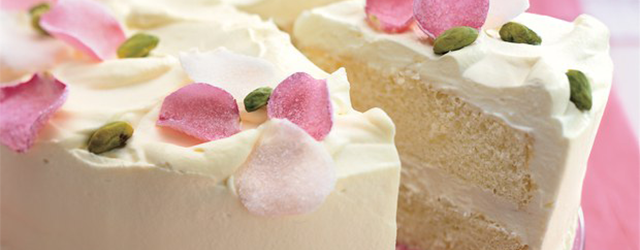 A white cake with white icing, decorated with rose petals