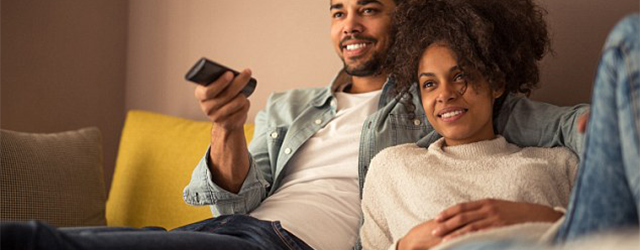 A couple watching TV in bed.