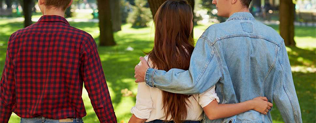 A woman holding hands with one partner and with her arm around another