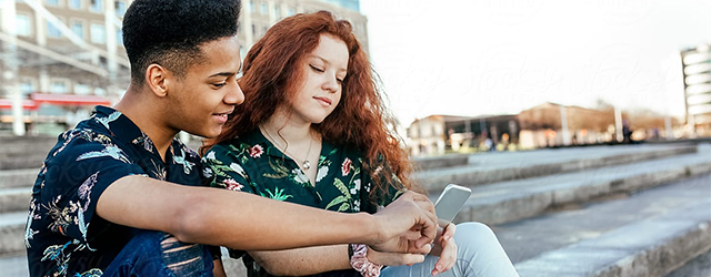 A teen couple looking at a phone together